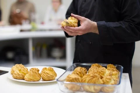 The cook prepares eclairs. Cut the eclairs and lay the cream Stock Photos
