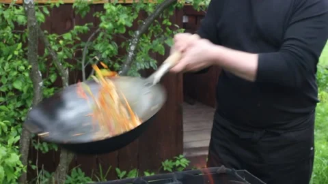 The cook prepares food in a wok on the fire. roasting meat, vegetables Stock Footage 134197934