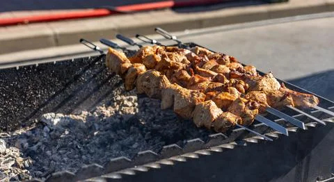 Cook prepares meat on coals in the open air Stock Photos