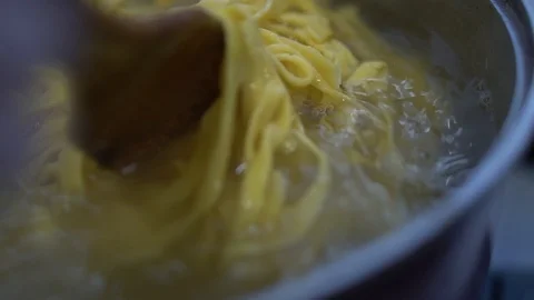 The cook prepares pasta while stirring the pasta is cooked in a saucepan, in Stock Footage 107077676