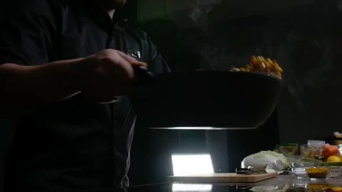 Cook prepares vegetables using the stir-fry technique in hot oil in a deep Stock Footage 274105415