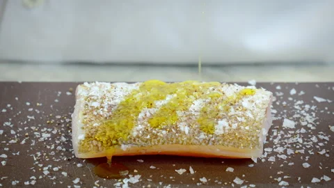 The cook prepares zander. The chef pours olive oil on the raw white fish fillet. Stock Footage 275247232