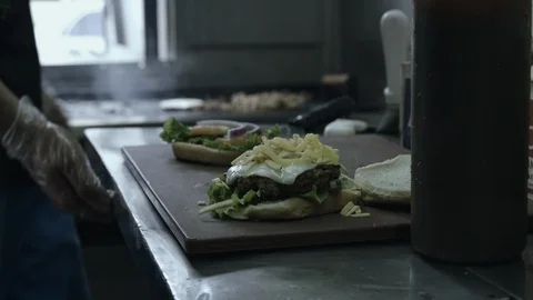 Cook preparing a cheesburger in restaurant kitchen Stock Footage 90610476