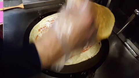 Cook preparing a crepe on a black pan Stock Footage 103879355