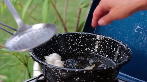 Cook preparing fried dumplings in a pan full of seed oil. Stock-Footage 135901554