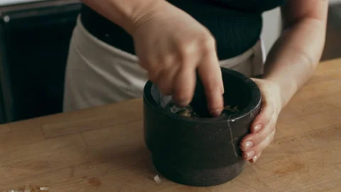 Cook preparing garlic using mortar and pestle for an octopus carpaccio dish in a Stock Footage 199456274