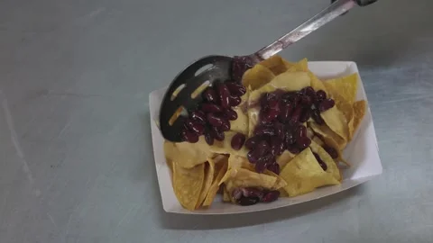 Cook preparing nachos dish adding black beans, close-up top view Video stock 246237561