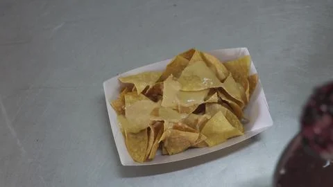 Cook preparing nachos dish adding black beans, close-up top view Stock Photos