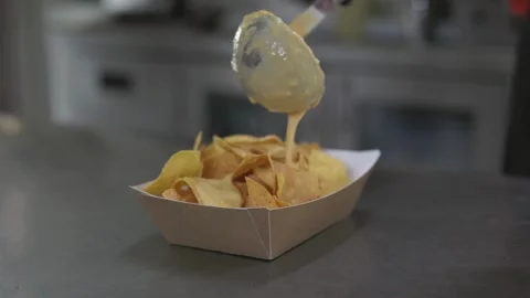 Cook preparing nachos dish with melted cheese sauce, close-up Stock Footage 246237444