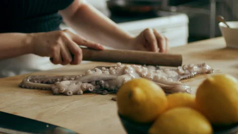 Cook preparing octopus on a cutting board in a large well appointed kitchen with Stock Footage 199455445