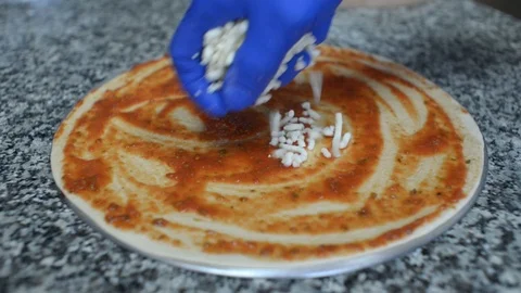 A Cook preparing a Pizza, applying Tomato and Mozzarella to a Dough Stock Footage 98043590
