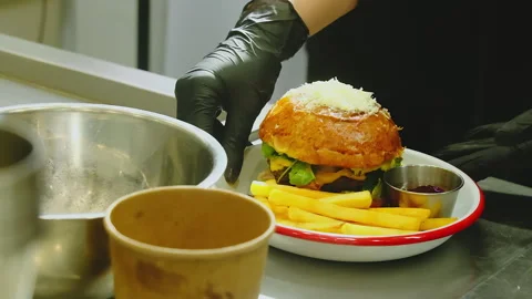 Cook presents plated burger and fries ready for pickup Stock Footage 325068955