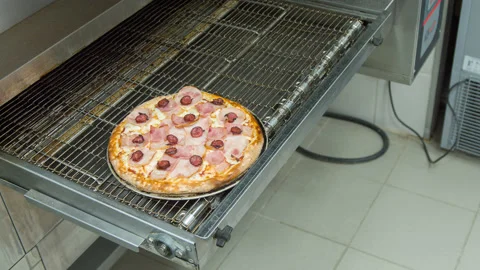 Cook pulls out a pizza of the oven Stock Footage 142400204