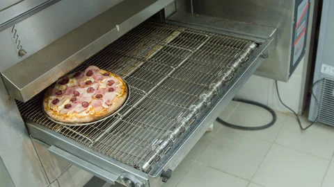Cook pulls out a pizza of the oven Stock Footage 142400782