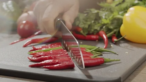 Cook pushes red chili pepper with sharp steel knife on the kitchen board Stock Footage 124066558