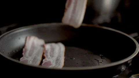 The cook puts the bacon in the pan his hands. Close up view Stock Footage 129574184