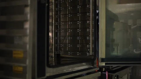 Cook puts a baking sheet with bakeware in the oven Vidéo 106460907