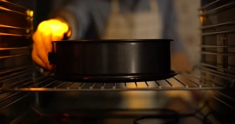 A cook puts a baking tin in the oven to bake a cake. Stock Footage 255516298