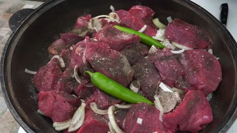 The cook puts beef meat and vegetables in a cauldron Stock Footage 198925809