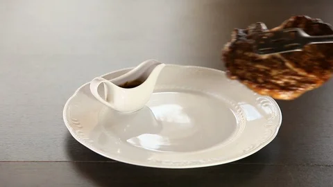 The cook puts the beef steak on the plate, decorates it with herbs, splashes it Stock Footage 115494476