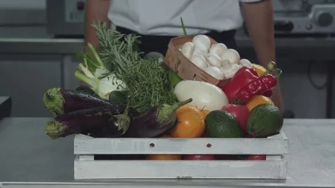 Cook puts a box with vegetables, greens and mushrooms on the table Stock Footage 80689222