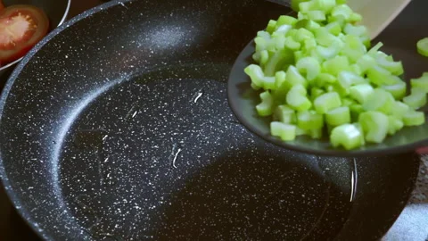 Cook puts chopped celery stalks in a pan for frying. Slow motion footage. Stock Footage 297249998