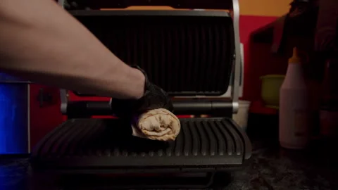 The cook puts the cooked shawarma in the electric grill Stock Footage 172494565