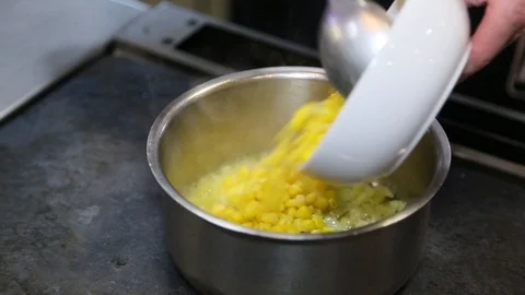 The cook puts the corn in a metal pan Stock Footage 129572279