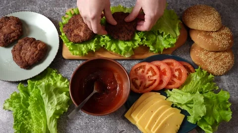 The cook puts cutlets on lettuce leaves. The process of making burgers Stock Footage 233338574