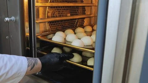 The cook puts the dough in the oven, baking oven, preparation for baking buns, a Stock Photos
