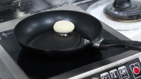 The cook puts the dough in the pan, and turns the pancakes, the oil boils on the Stock Footage 166645270