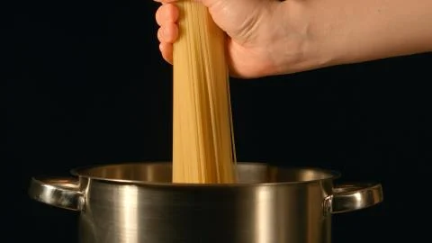 Cook puts down a bunch of spaghetti in a steel pot Stock Photos