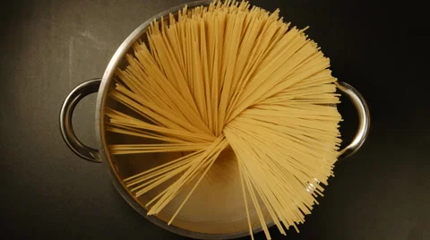 A cook puts down a spaghetti in a steel pot (round) Stock Footage 61033370
