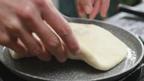 The cook puts flat bread into the frying pan. Stock Footage 246860858