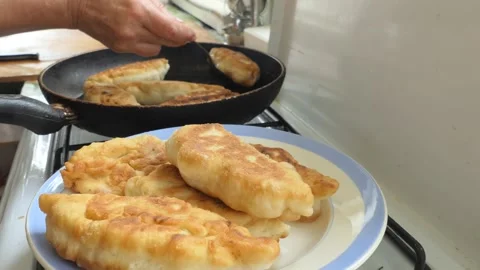 The cook puts fried cabbage pies on a plate from the pan. Stock-Footage 138141550
