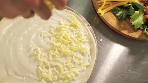 Cook puts his hands on the cheese on the pizza Stock Footage 130557600