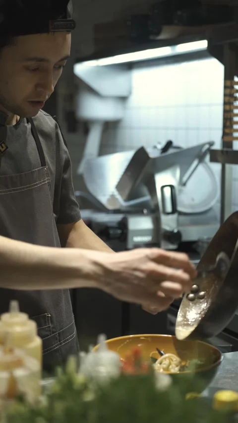 The cook puts a hot dish from the pan on a plate Stock Footage 247030422
