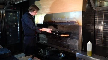 The cook puts a piece of ready-made freshly prepared steak on a chopping board Stock Footage 85670904