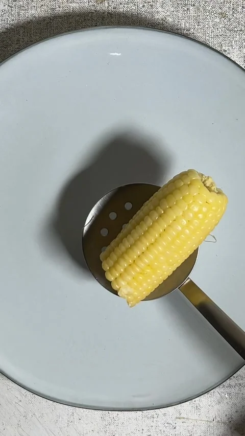 Cook puts pieces of boiled half an cob of corn into plate by slotted spoon Video stock 282107544