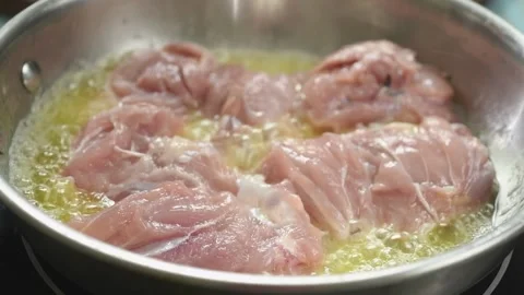The cook puts raw chicken meat in the frying pan. Stock Footage 210717872