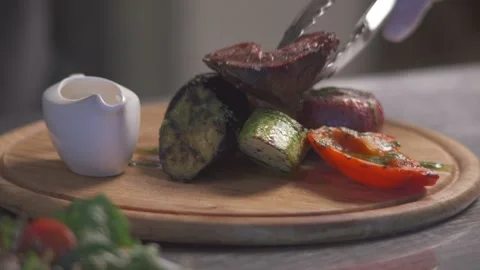 Cook puts roasted meat to garnish vegetables. Part 1. Video stock 89058623