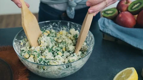 Cook puts salad on a serving plate. Prepared vegetarian salad with herbs and Stock Footage 136674248