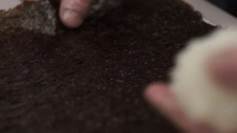 The cook puts a sheet of nori on the table and puts rice on it. Stock Footage 106670402