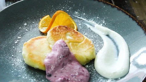 The cook puts a slice of orange on cheesecakes with sweet sauce Stock Footage 112508451