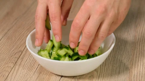 The cook puts sliced cucumbers in a plate and pours gazpacho. Stock Footage 112264434