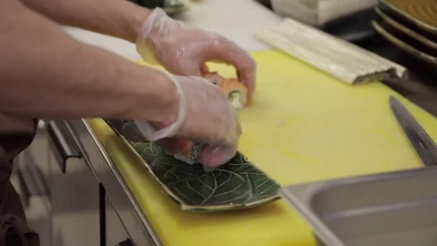Cook puts sushi on plate in kitchen of restaurant Stock Footage 75788435