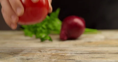 The cook puts two tomatoes on the Board. in the background, onions and parsley. Stock Footage 113422139