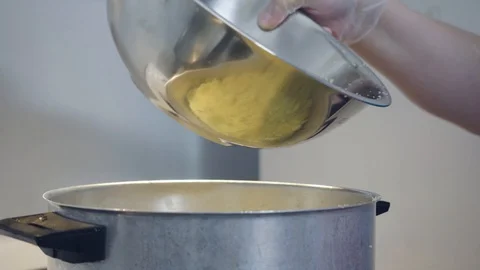 A cook is putting couscous flour into a large pot Stock Footage