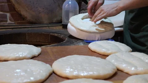 The cook putting the dough on a baking pillow and then placing it in a tandoor. Stock Footage 321815219