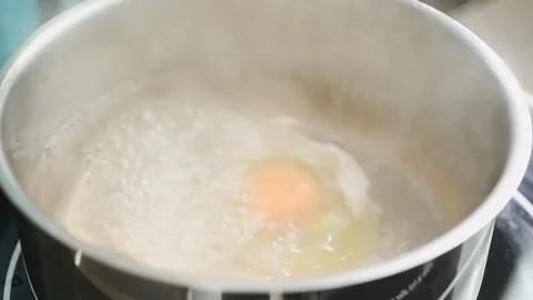 The cook putting egg into hot boiling water to make poached egg. Stock Footage 194921568